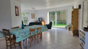 Un comedor amplio con una mesa dispuesta para cuatro, un sofá y un televisor al fondo.