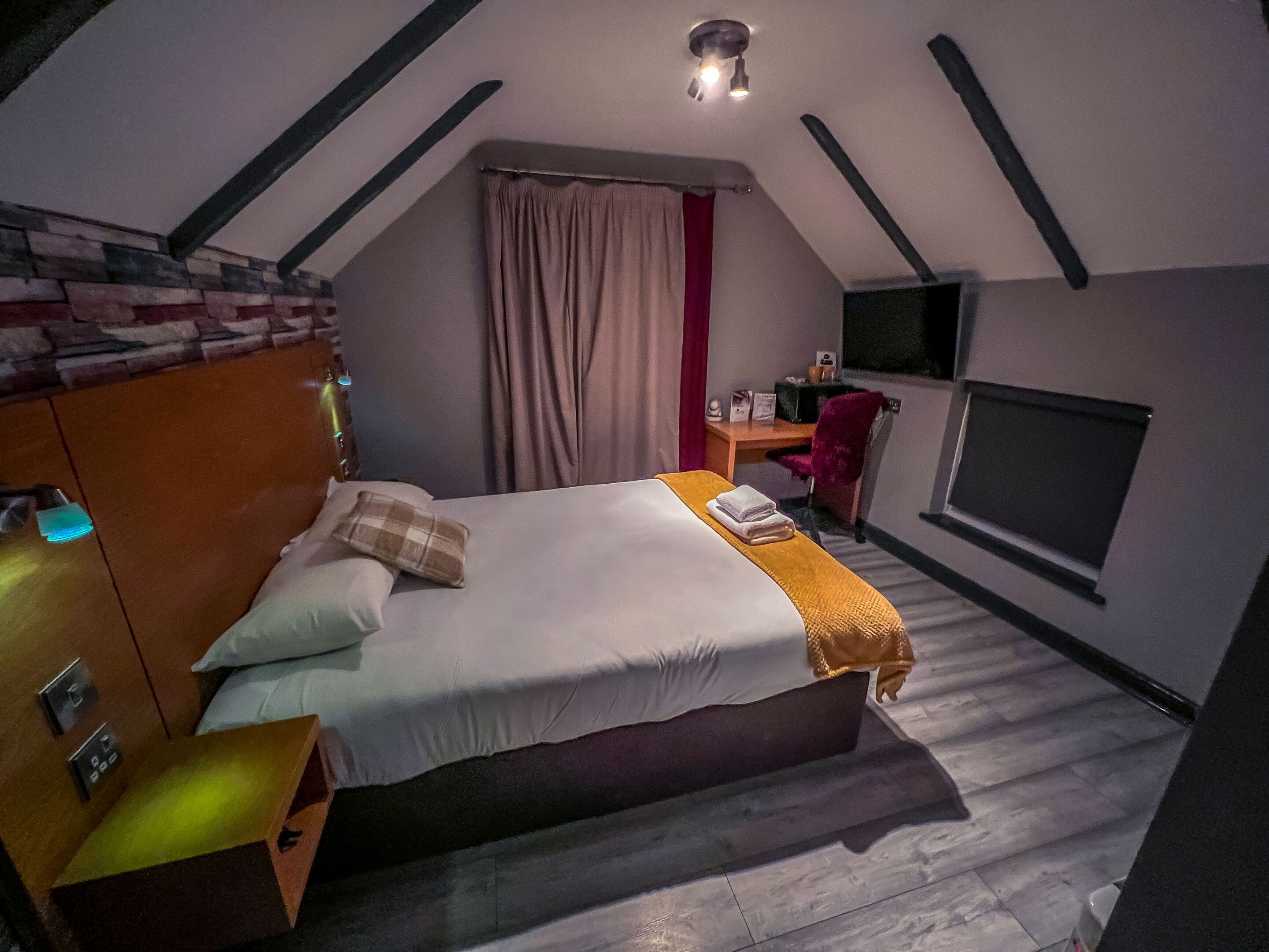 Un dormitorio con cama, escritorio, silla y televisor.