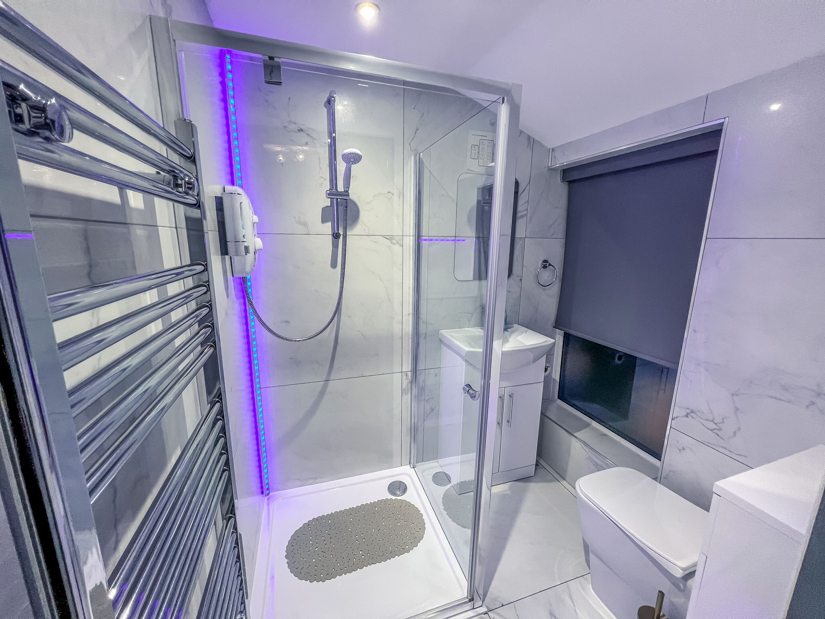 Une salle de bain moderne dotée d’une douche à parois de verre, de toilettes et d’un lavabo.