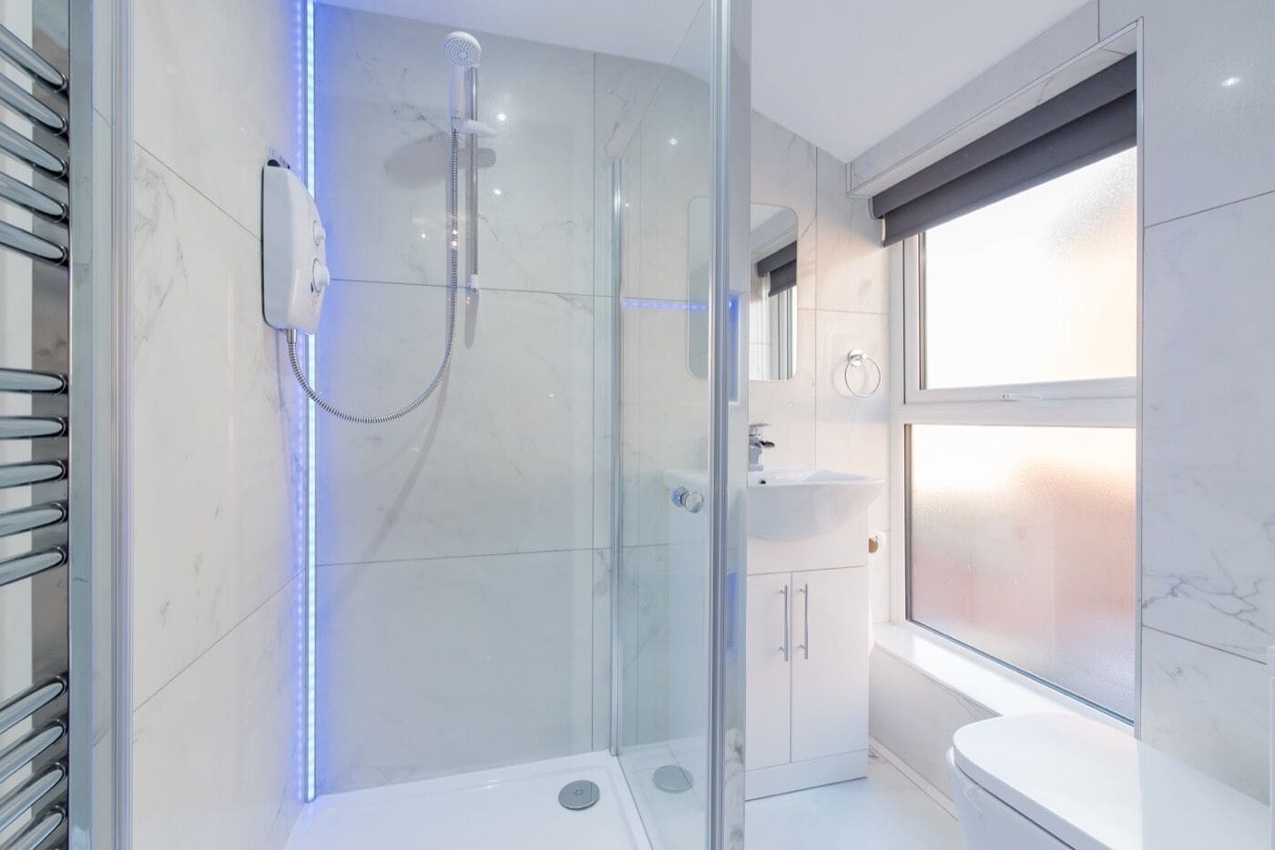 A modern bathroom with a glass-enclosed shower, a white sink, and a toilet.