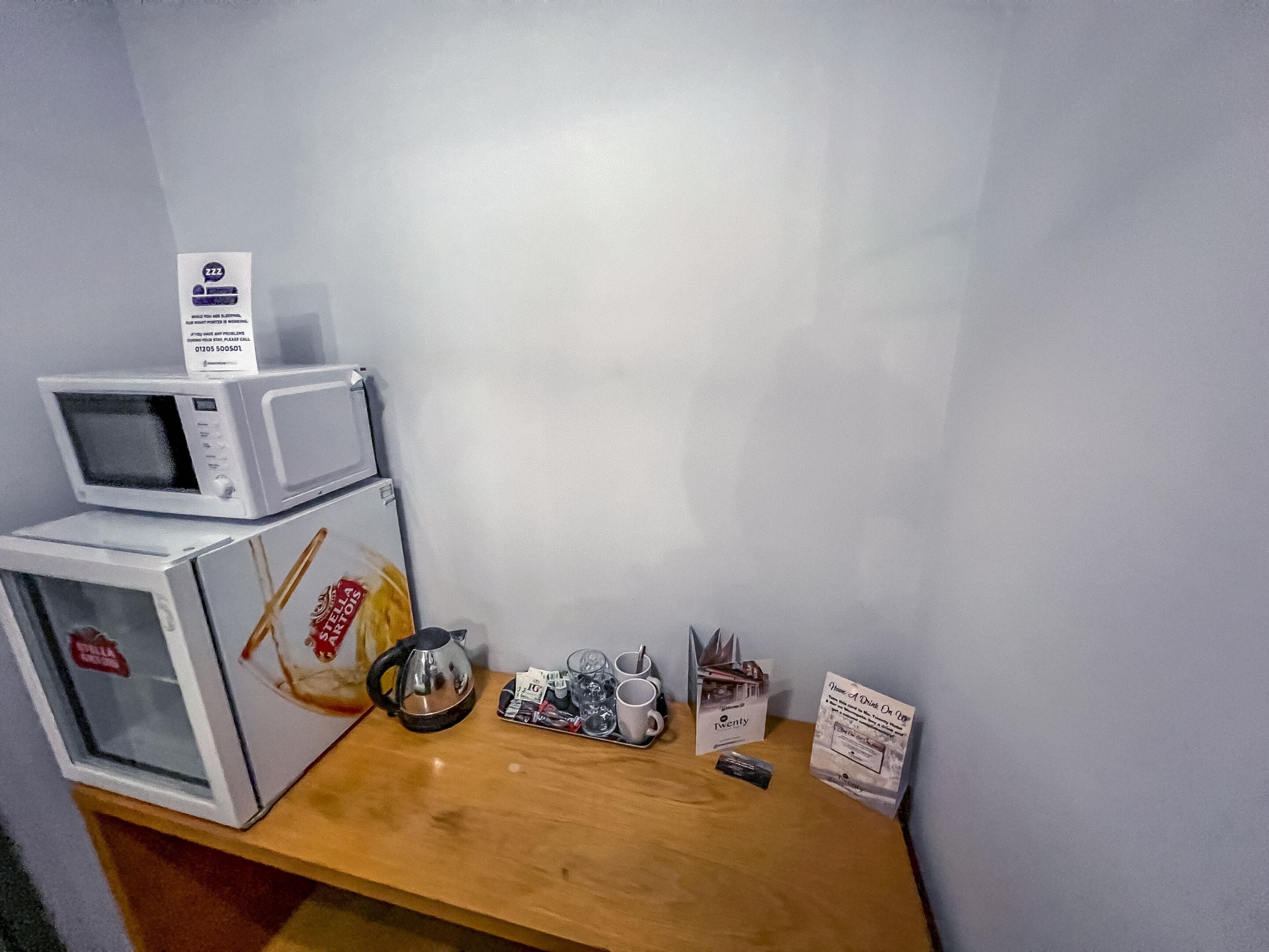 Una kitchenette pequeña con microondas y cafetera sobre una encimera de madera.