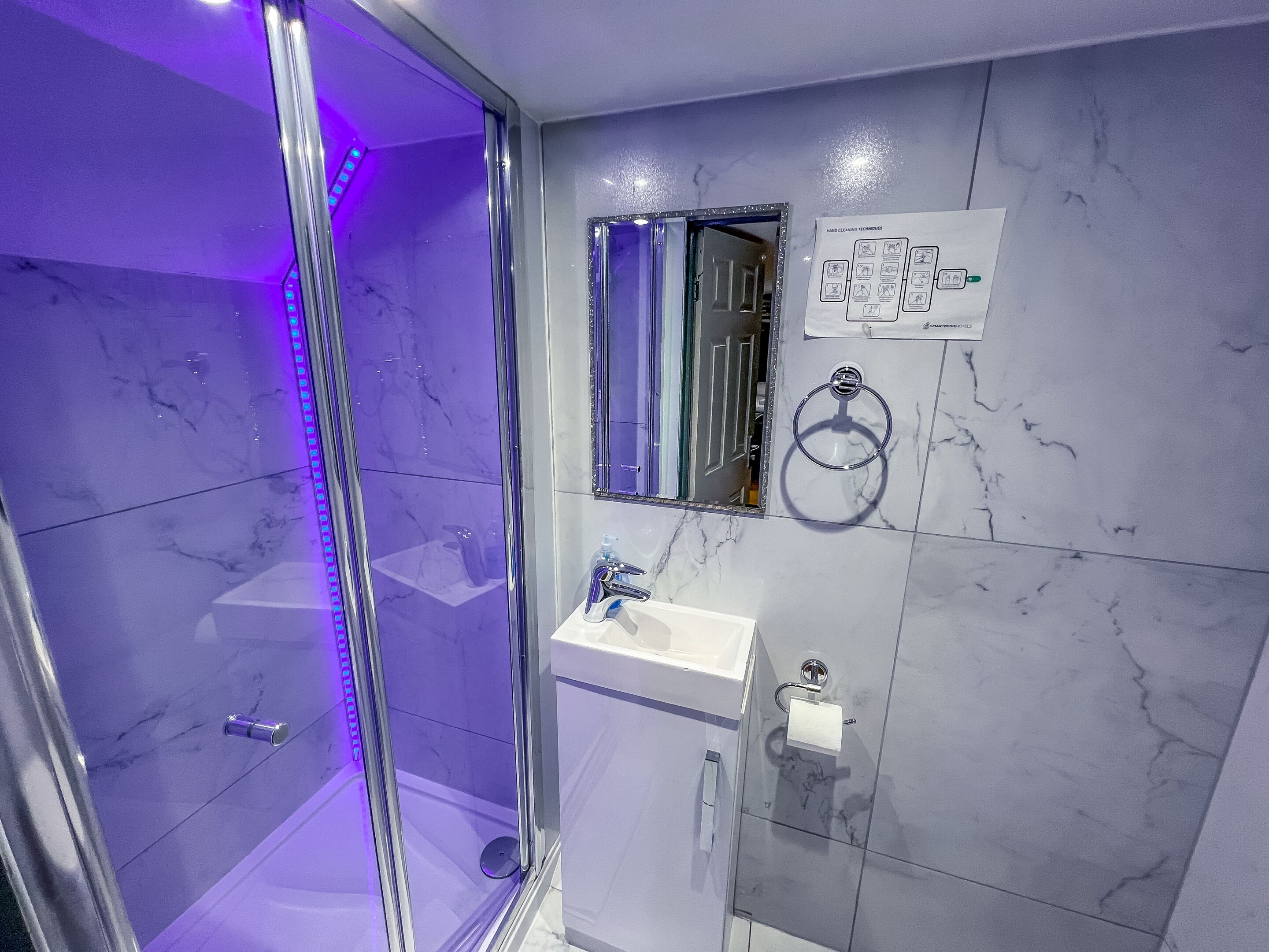 Un baño moderno con cabina de ducha de vidrio, lavamanos y espejo.