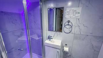 Un baño moderno con cabina de ducha de vidrio, lavamanos y espejo.