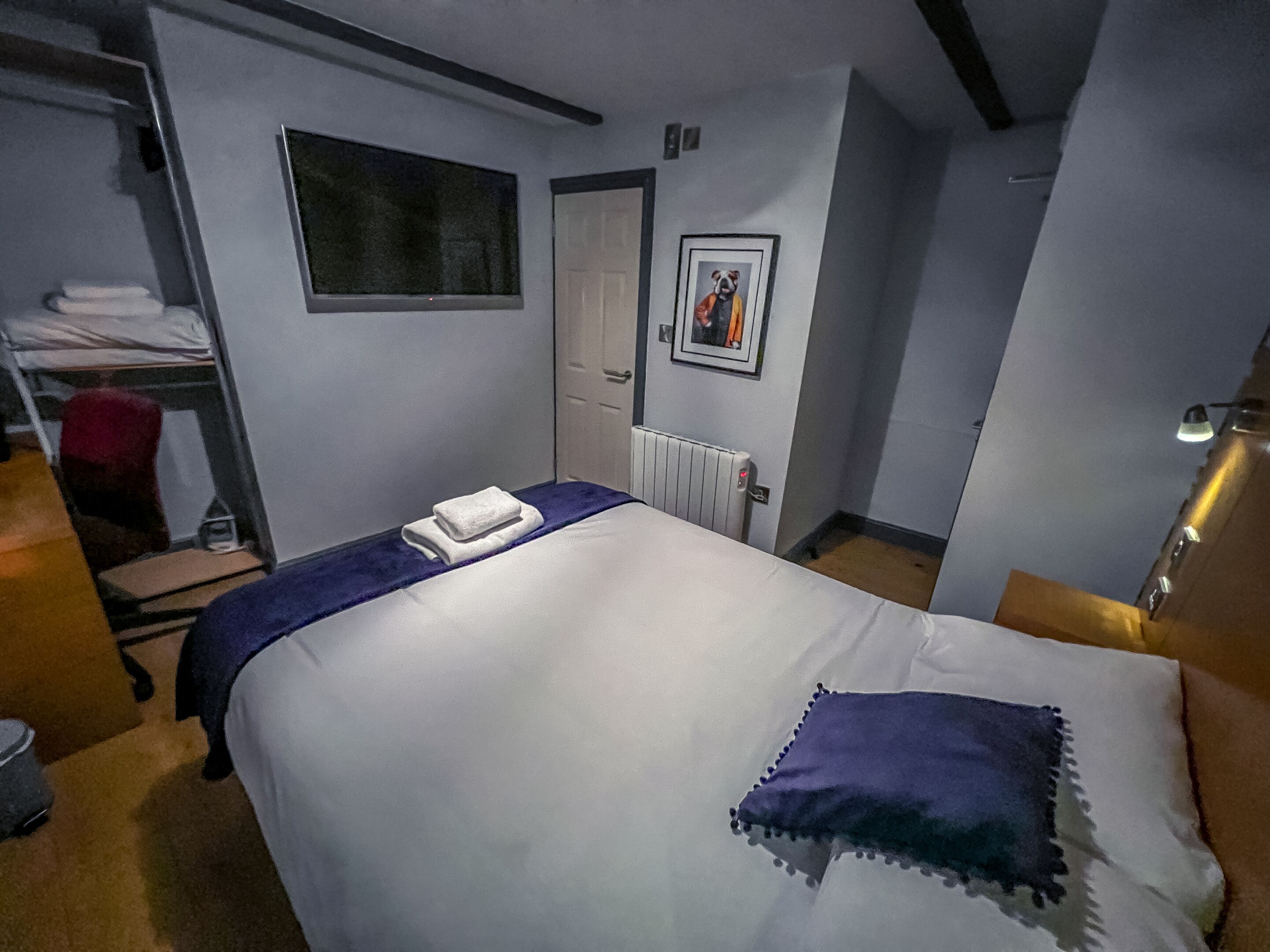 Una habitación de hotel con cama, radiador, puerta y ventana.