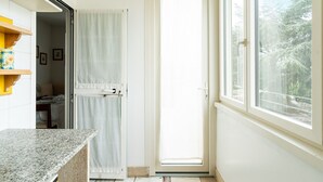 Een badkamer met douche, toilet, wastafel en een raam met uitzicht op bomen.