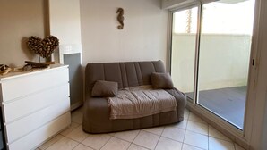 A living room with a sofa, a heart-shaped decoration, and a wall-mounted piece. - Studio in Saint-Cyprien – Beach access, pool, terrace (Saint-Cyprien)