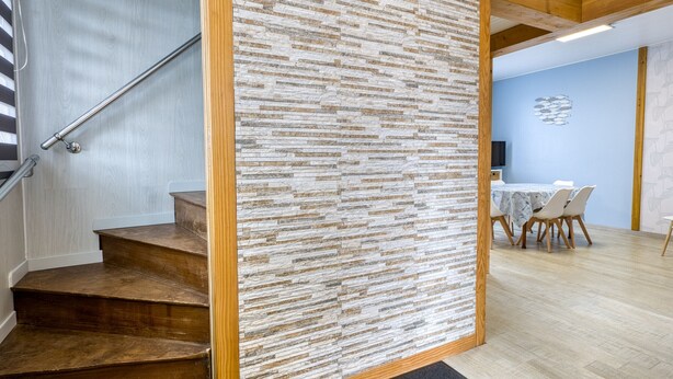 A staircase leading to a room with a stone wall, a dining area with a table and chairs, and a ceiling with exposed beams. - Family Home with Garden near Beach in Châtelaillon – Sleeps 6 (Châtelaillon-Plage)