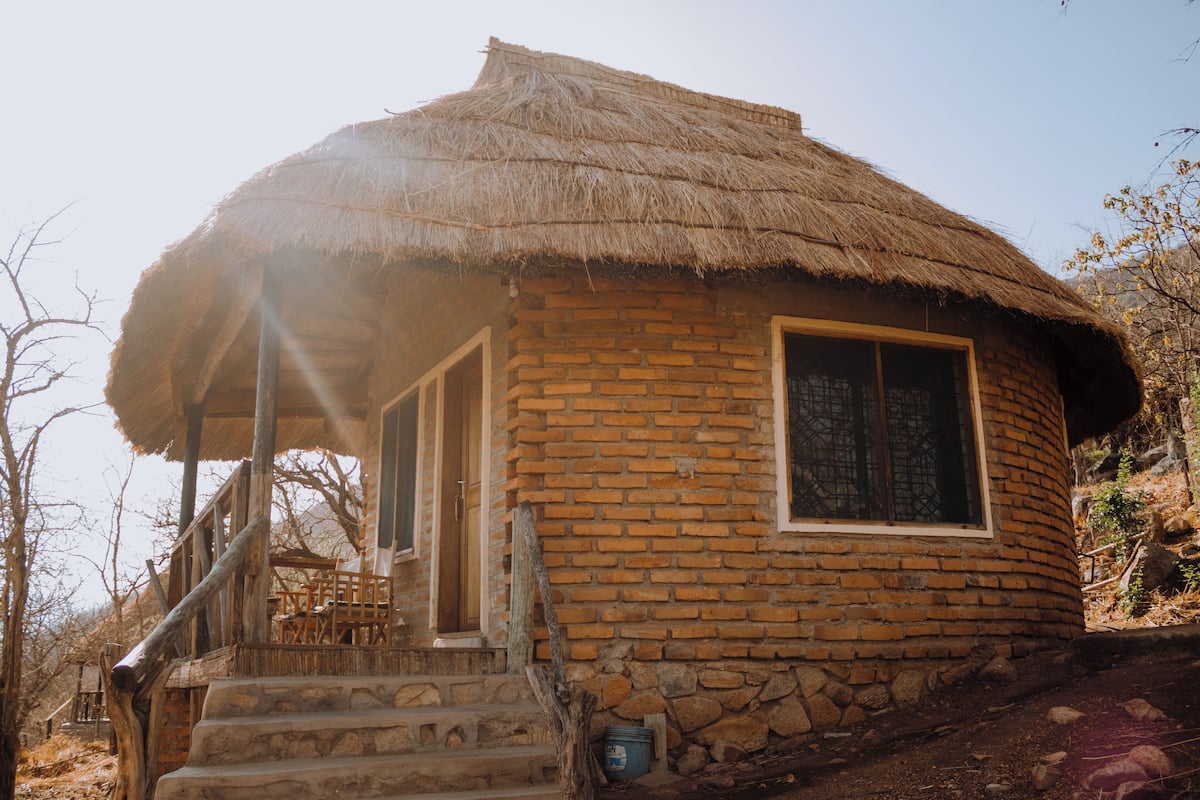 Una casa con techo de paja y una escalera de piedra que lleva a una puerta de madera.