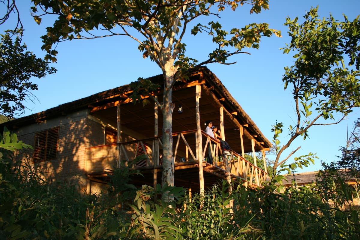 Una casa de madera con balcón, rodeada de vegetación densa.