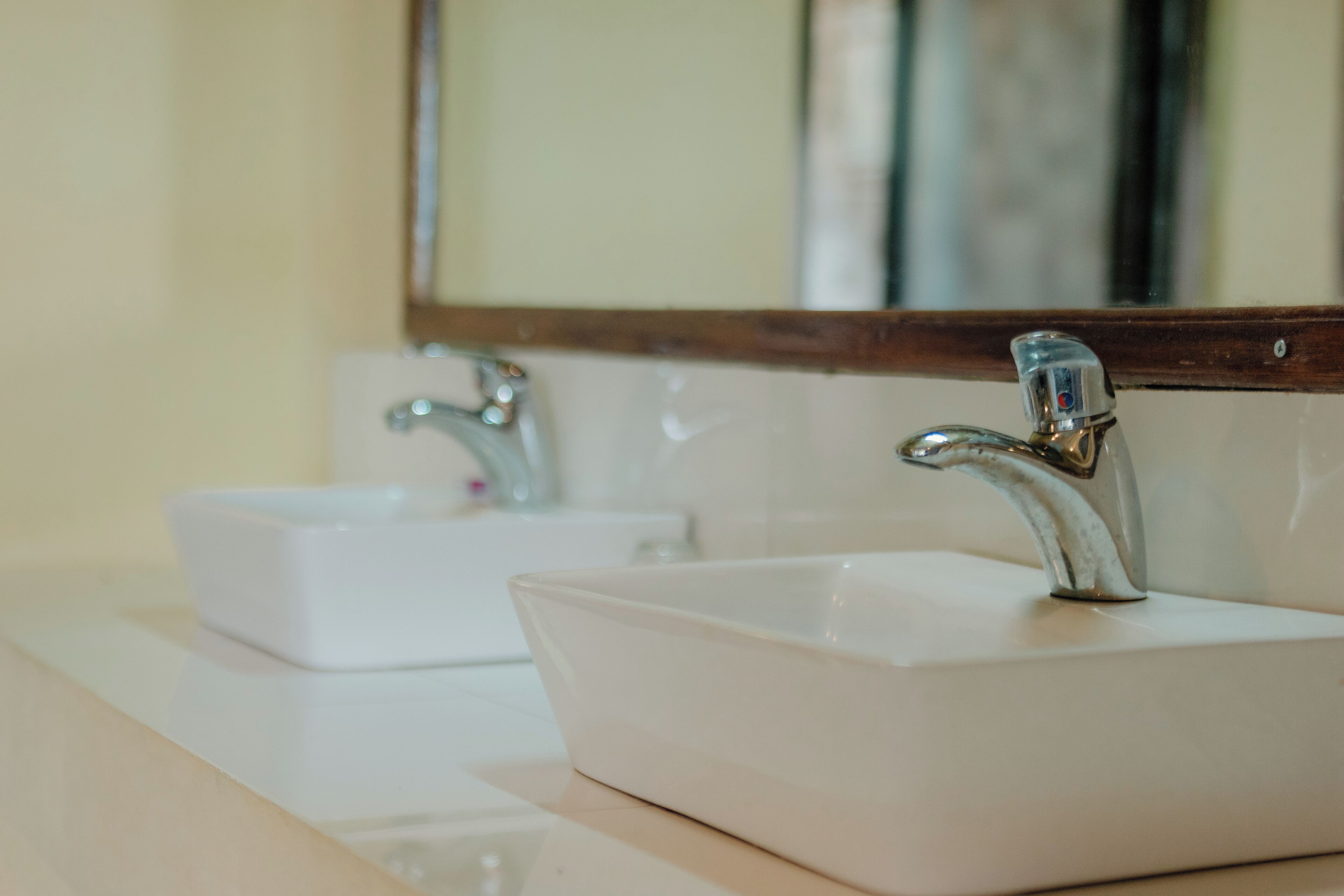 Un baño con dos lavamanos blancos y un espejo encima.