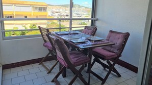 A balcony with a table and chairs, a view of buildings and a clear sky. - Modern 4-person apartment with pool and parking in Cap d'Agde (Cap d'Agde)