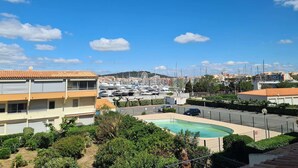A residential area with a swimming pool, a parking lot, and a marina in the background. - Modern 4-person apartment with pool and parking in Cap d'Agde (Cap d'Agde)