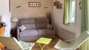 A living room with a sofa, two chairs, a small table, a lamp, and a window with curtains.
