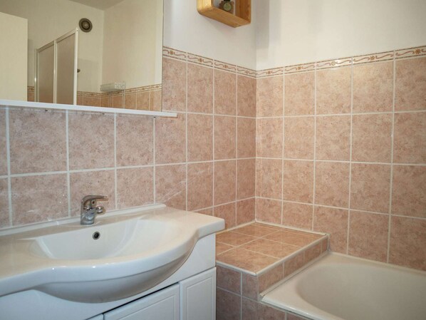 A bathroom with a sink, mirror, and bathtub.