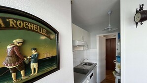 A kitchen with a sink, cabinets, and a clock on the wall. - T2 Apartment with Parking near La Rochelle Old Port (La Rochelle)