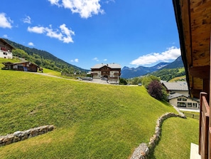 Une vue sur la montagne avec un bâtiment de style chalet, un mur en pierre et un ciel dégagé.
