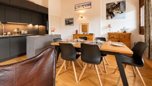 A modern kitchen with dark cabinets, a wooden dining table, and black chairs. - 3-bedroom duplex at the foot of the slopes with pool and parking (Flumet)