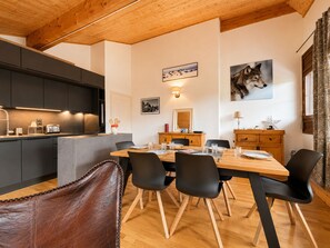 Una cocina moderna con gabinetes oscuros, una mesa de comedor de madera y sillas negras.