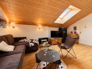 Un salon confortable avec un canapé, une table basse, un téléviseur et un réfrigérateur.