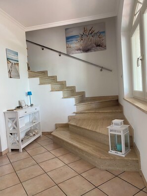 Un escalier avec une rampe, une console blanche surmontée d’une lampe et une petite lanterne.