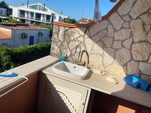 A balcony with a stone wall, a sink, and a towel.