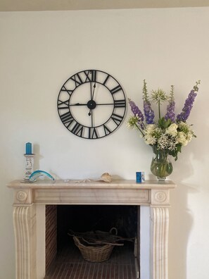 A wall-mounted clock, a vase with flowers, and a fireplace mantel with decorative items.