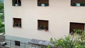 Ein mehrgeschossiges Gebäude mit Balkonen, Fensterläden und Blumentöpfen.