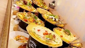 Buffet com diversos pratos, incluindo saladas, carnes e frutas, dispostos em uma mesa longa.