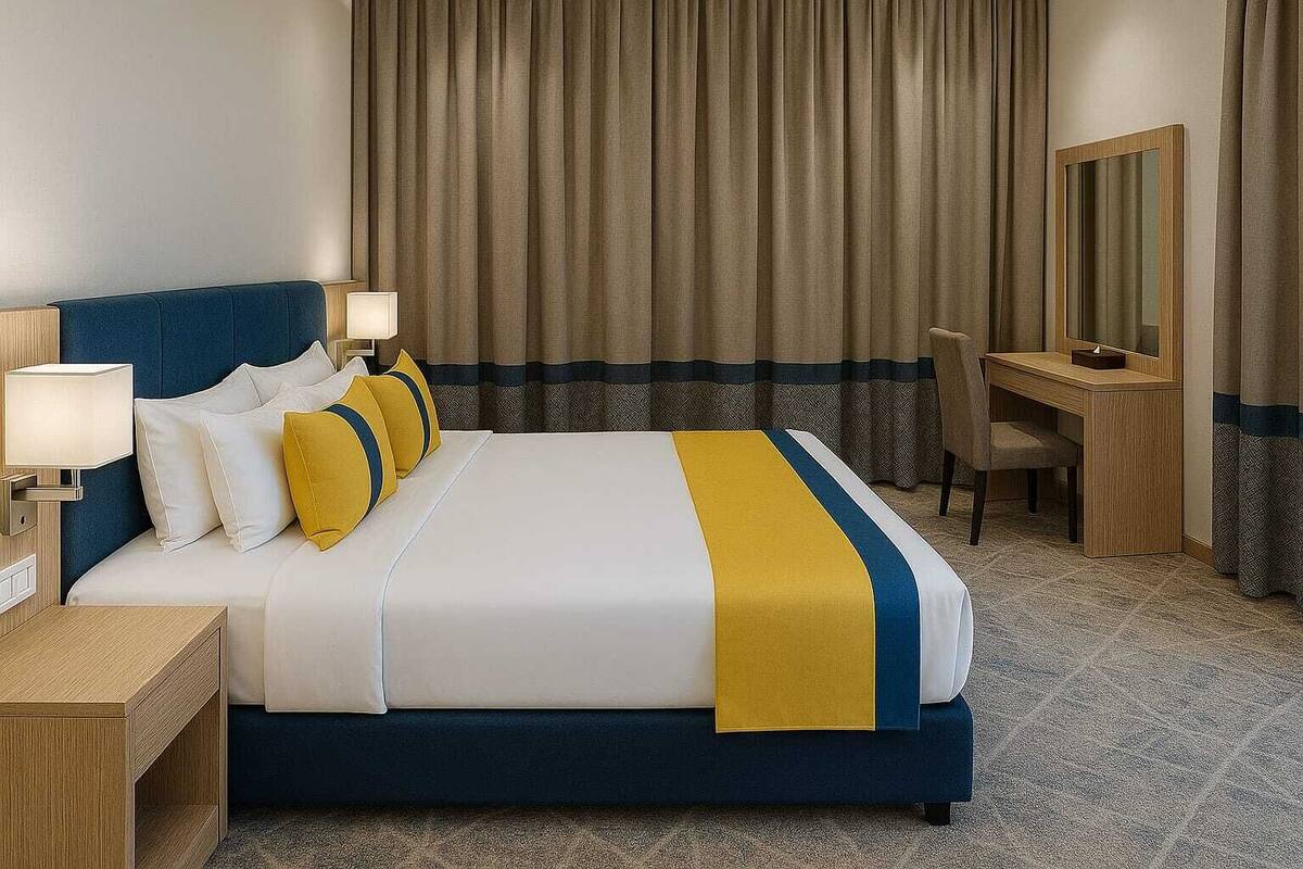 A hotel room with a large bed, bedside tables, a desk, and a mirror.