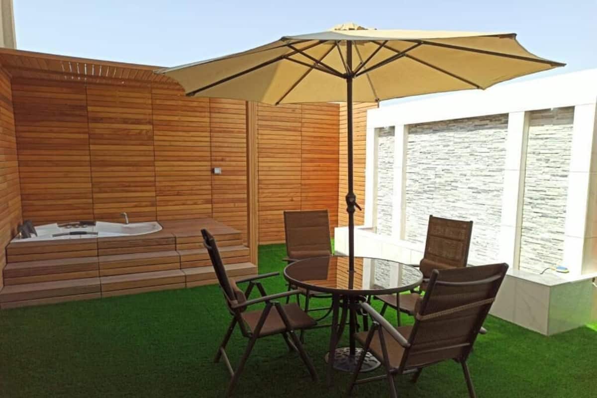 A patio with a round table, four chairs, and a large umbrella.