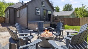 Uma casa com área de varanda, cadeiras Adirondack e lareira.