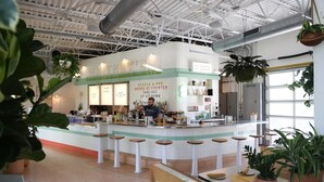 Un espace bar avec un comptoir, des tabourets et des plantes en pot.