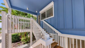 Une maison bleue avec un escalier blanc menant à une terrasse.