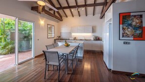 Una cocina moderna con armarios blancos, una isla central y un comedor con mesa y sillas.