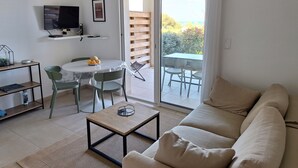 A modern living room with a sofa, a coffee table, and a dining area with chairs and a table.