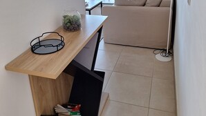 A modern, minimalistic living space with a wooden desk, a sofa, and a view of the outdoors.