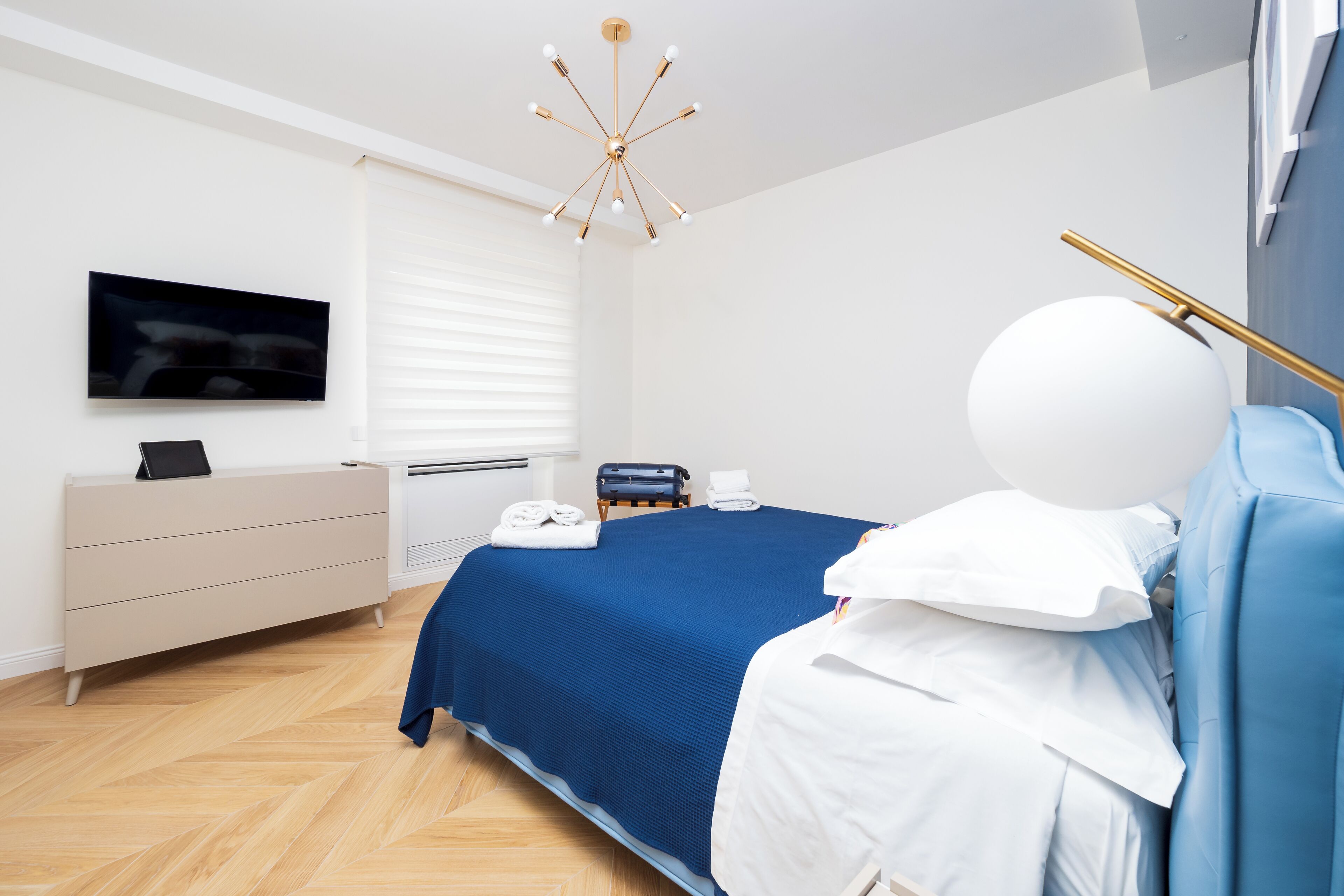 Un dormitorio moderno con una cama, un aparador, un televisor y un objeto esférico único sobre la cama.