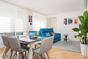 A modern living room with a dining area, featuring a blue sofa, a glass coffee table, and a laptop on the dining table. - Regina Vittoria Relais (Vico Equense)