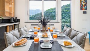 A breakfast table set with croissants, orange juice, and coffee, overlooking a scenic view. - De Vivo Realty - Regina Vittoria Relais EcoSmart Luxury Home SPA (Vico Equense)