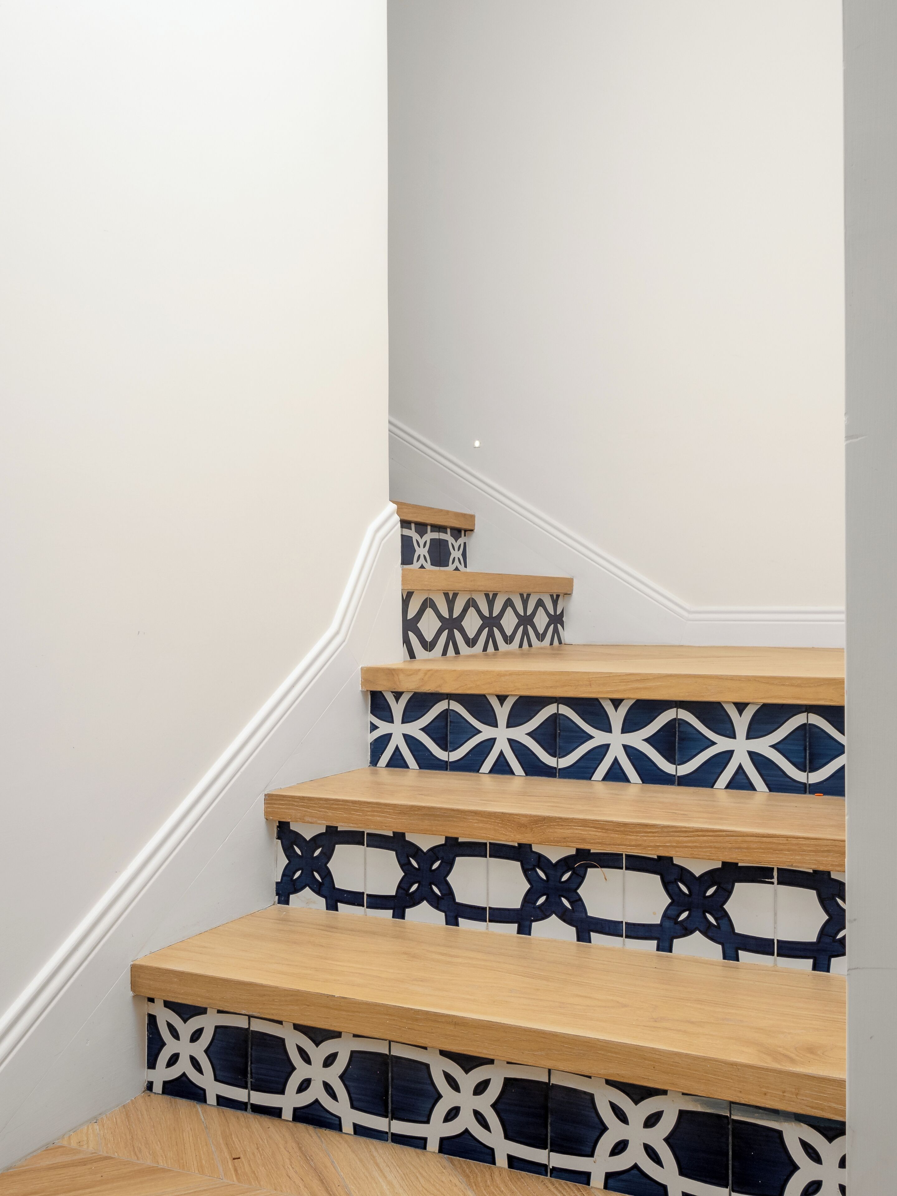 A staircase with wooden steps and decorative blue and white tiles.