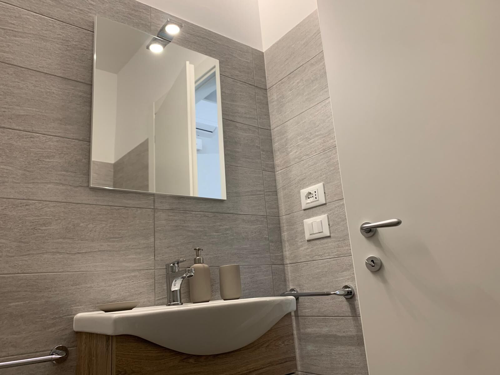 A modern bathroom with a large mirror, a sink with a wooden vanity, and a towel rack.