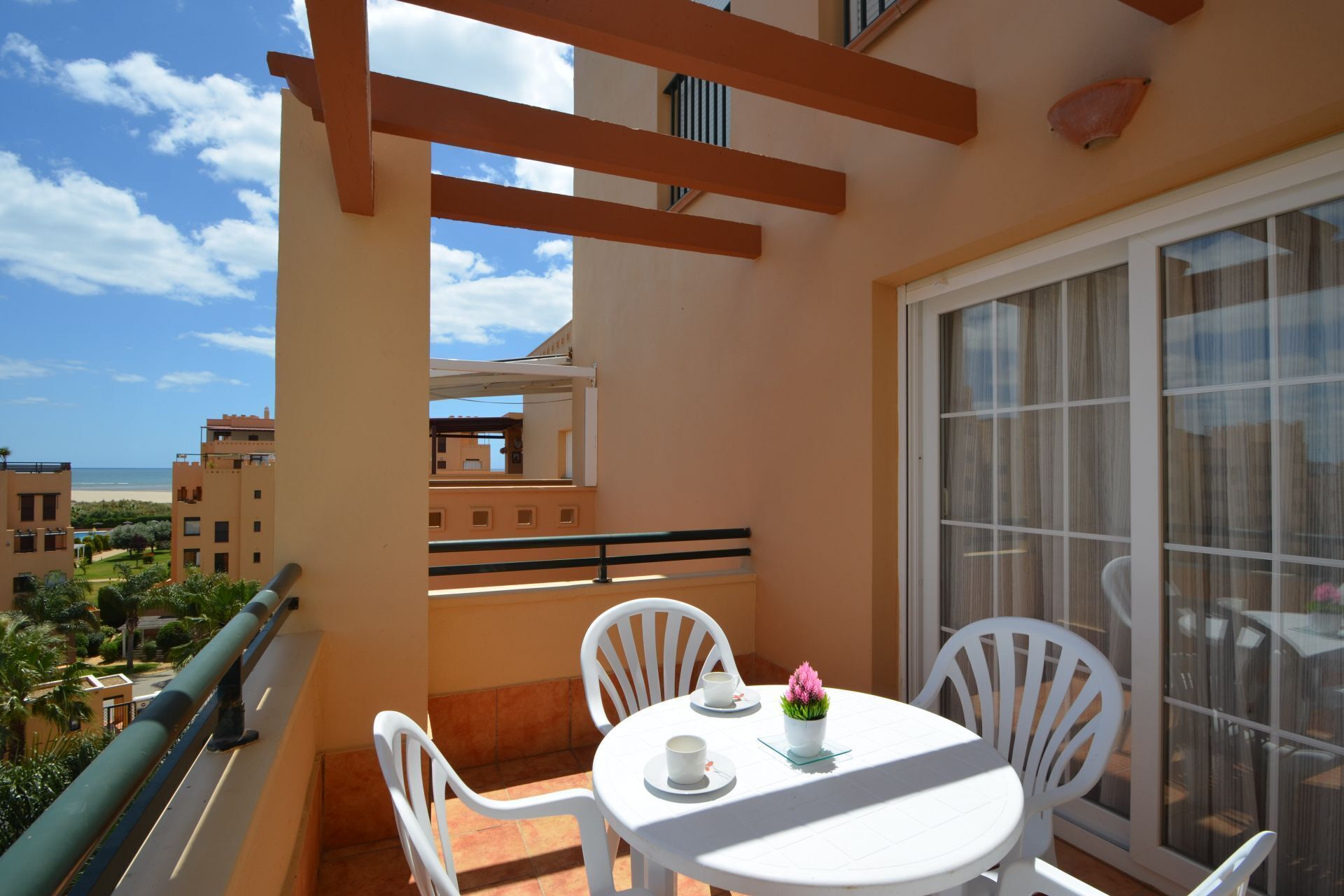 A balcony with a white table, two white chairs, and a potted plant.