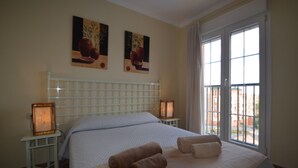 Een hotelkamer met een groot bed, twee nachtkastjes, een raam met uitzicht en twee aan de muur bevestigde schilderijen.