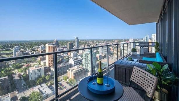 Ein Balkon mit Blick auf die Stadt, ein runder Tisch mit einer Flasche und eine Sitzecke mit Kissen.