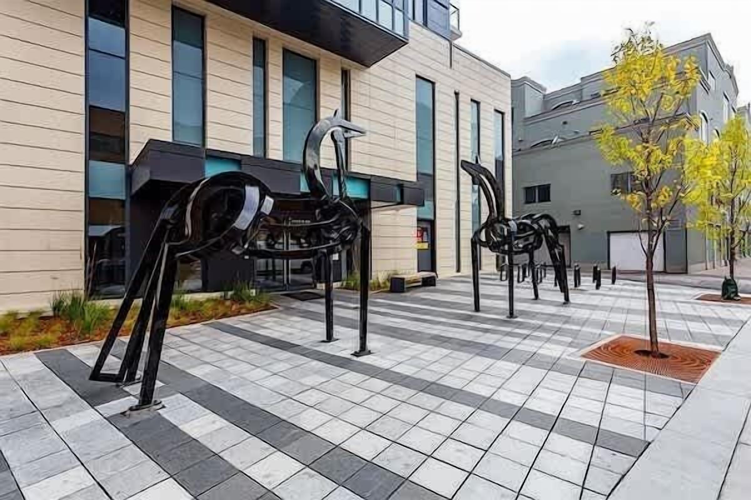 Een modern gebouw met een betegeld plein en abstracte sculpturen.