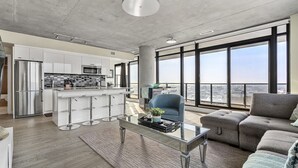 Ein modernes Apartment mit Küche, Essbereich und großem Fenster mit Stadtblick.