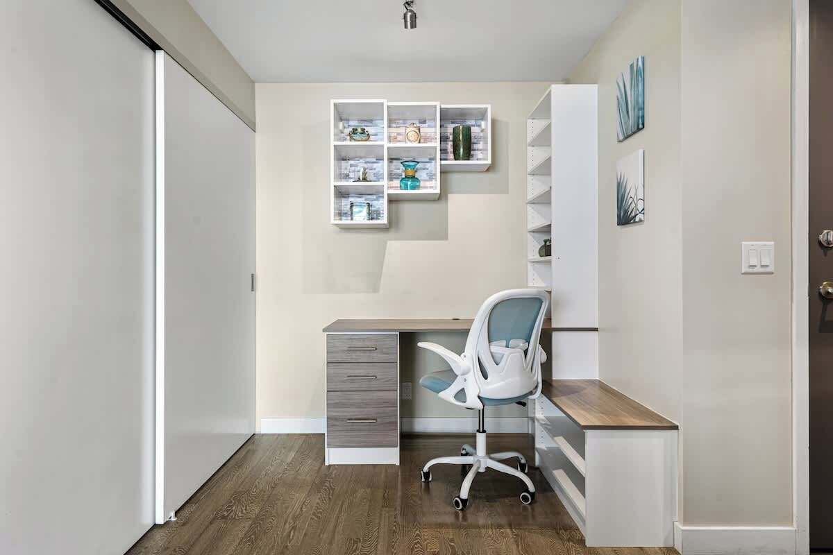 Um espaço de escritório moderno com escrivaninha, cadeira e estante embutida.