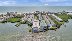Un hotel costero con varias edificaciones, un puerto deportivo y una playa al fondo.