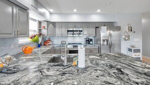 Una cocina moderna con encimeras de granito, electrodomésticos de acero inoxidable y una isla central.