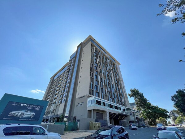 A tall, modern building with a glass facade and a prominent entrance. - Sandton Smart Apartment Thirty-One (Sandton)